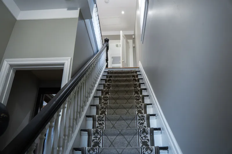 Staircase with patterned runner and wood balustrade